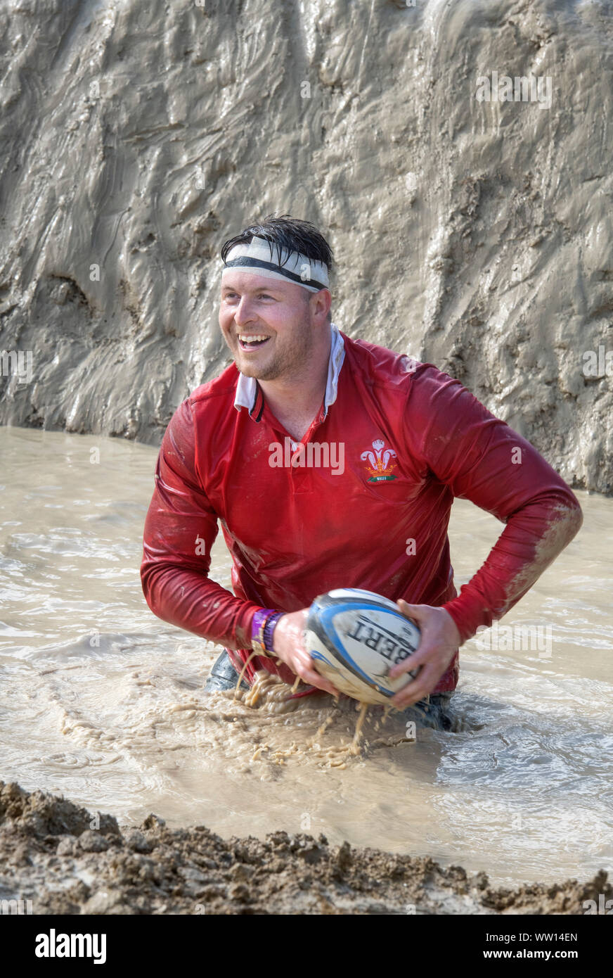 Ein Wettbewerber gekleidet als Wales Rugby Player auf der 'Mud Mile' an der haltbaren Mudder Ausdauer Event im Badminton Park, Gloucestershire, Großbritannien Stockfoto