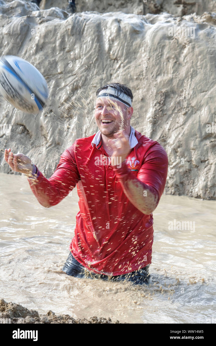 Ein Wettbewerber gekleidet als Wales Rugby Player auf der 'Mud Mile' an der haltbaren Mudder Ausdauer Event im Badminton Park, Gloucestershire, Großbritannien Stockfoto