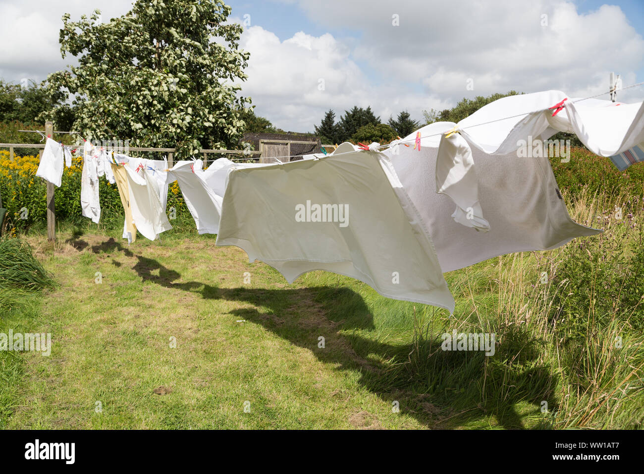 Wäscheleine mit weißer Bettwäsche an einem windigen Tag Stockfoto