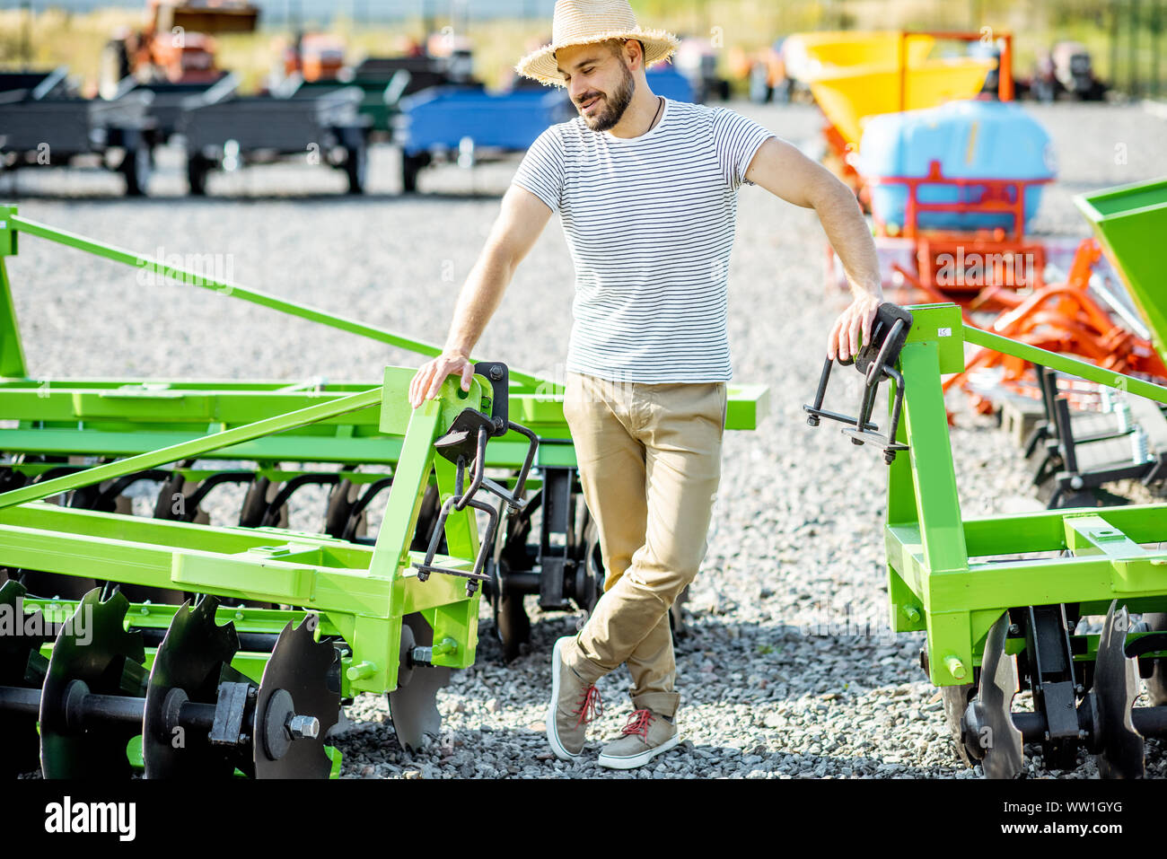 Portrait einer jungen Agrarwissenschaftler stehen in der Nähe der Pflug im Boden der Shop, kaufen neue landwirtschaftliche Maschinen für die Landwirtschaft Stockfoto