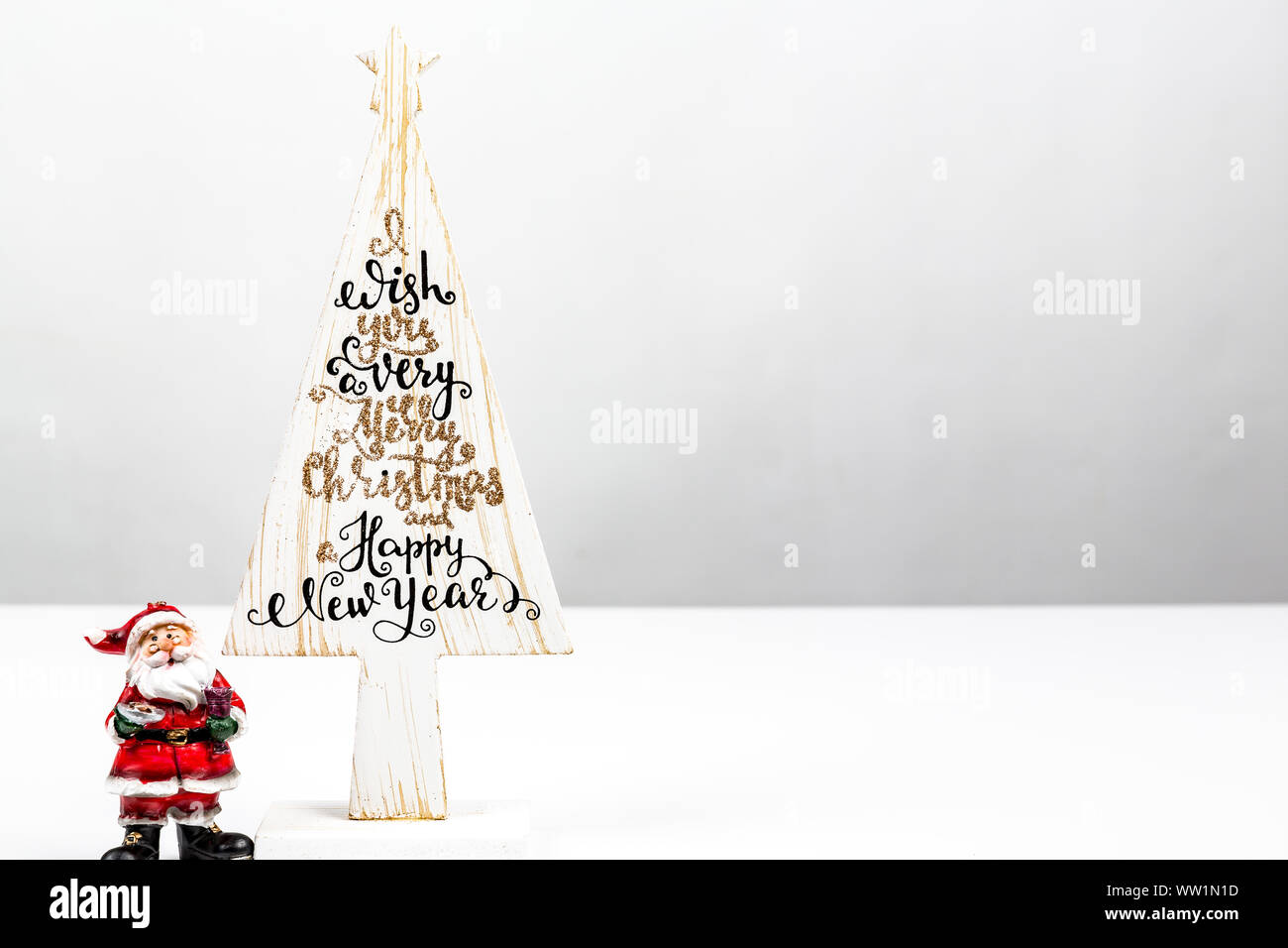 Schöne Minimal Weihnachten Holz weiß Baum mit Frohe Weihnachten und ein glückliches neues Jahr geschrieben, mit kleinen Santa Claus, auf weißem Hintergrund Stockfoto