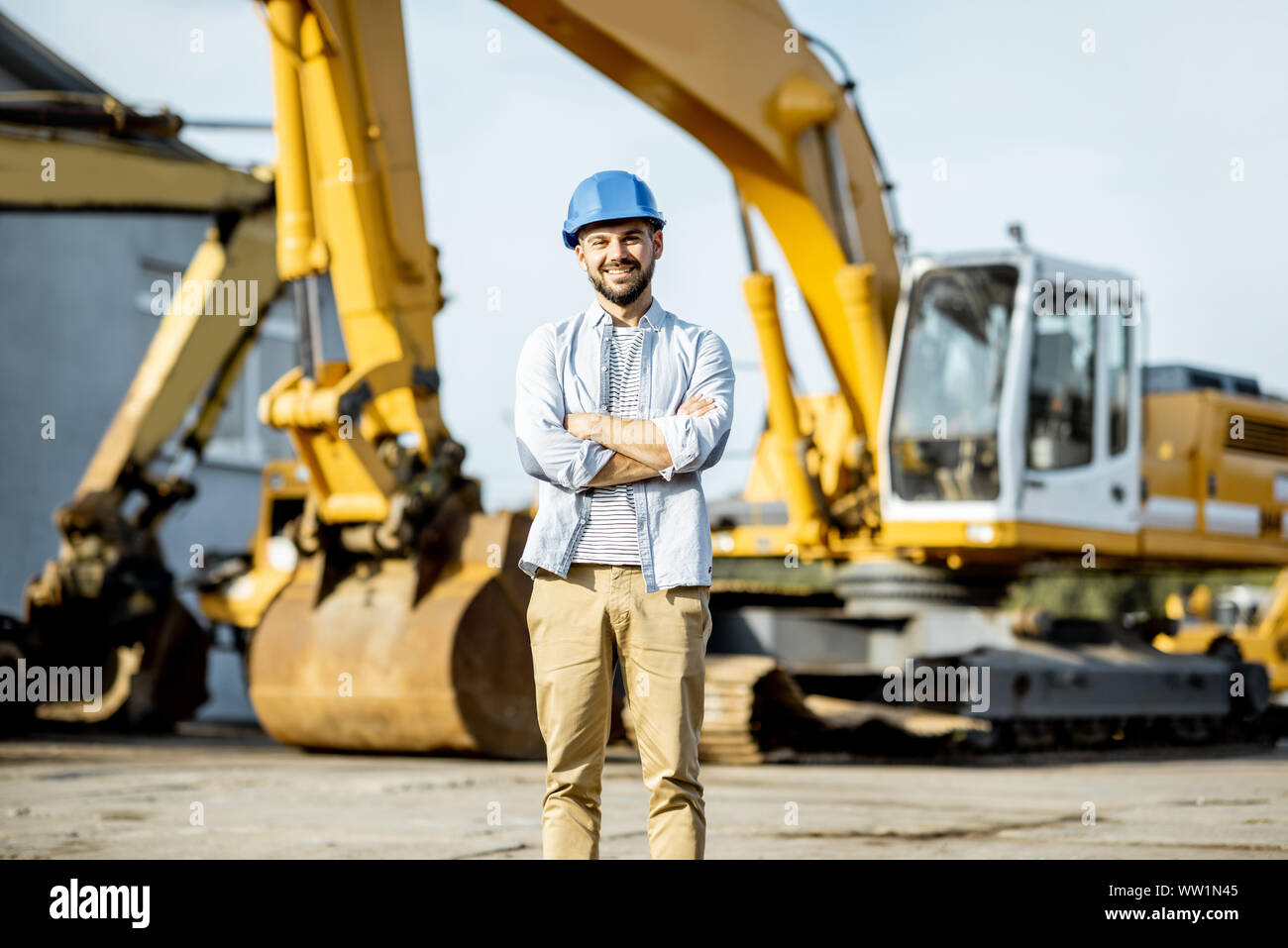 Porträt einer stattlichen Builder stehen auf dem offenen Gelände des Shop mit schweren Maschinen für den Bau Stockfoto