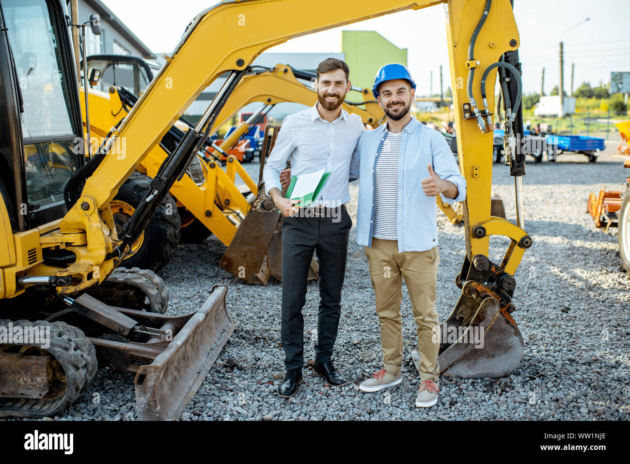Builder Wahl schwere Maschinen für Bau, im Gespräch mit einem Verkaufsberater im Freigelände der einen Shop mit speziellen Fahrzeugen Stockfoto