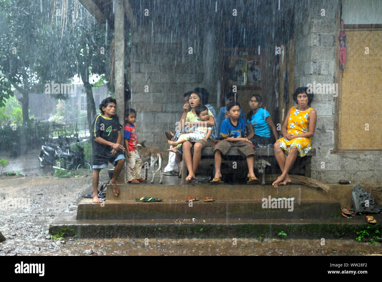 Bali, starker Regen ländliche Gemeinde Lovina. 2000s. Frauen und Familienmitglieder, die bei sehr starkem Regen auf der Veranda ihres Hauses sitzen. Indonesia Lovina. Insel Bali HOMER SYKES Stockfoto