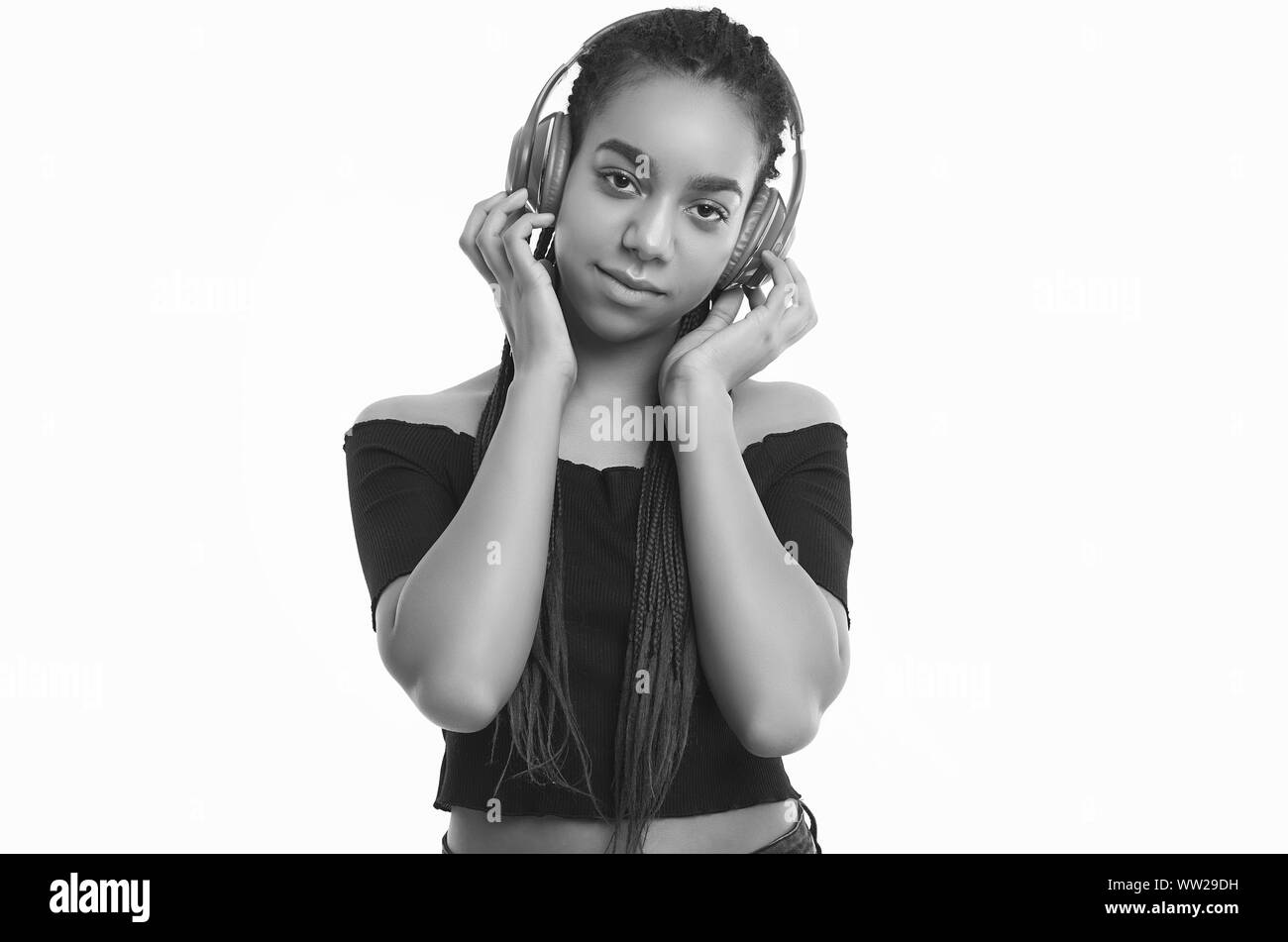 Portrait von wunderschönen afrikanischen brunette teenage Mädchen mit Dreadlocks Musik hören über kabellose Kopfhörer studio Hintergrund isoliert Stockfoto
