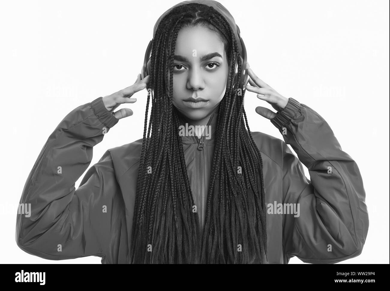 Portrait von wunderschönen afrikanischen brunette teenage Mädchen mit Dreadlocks tragen einen roten windbreaker Musik hören über kabellose Kopfhörer auf dem Bolzen isoliert Stockfoto