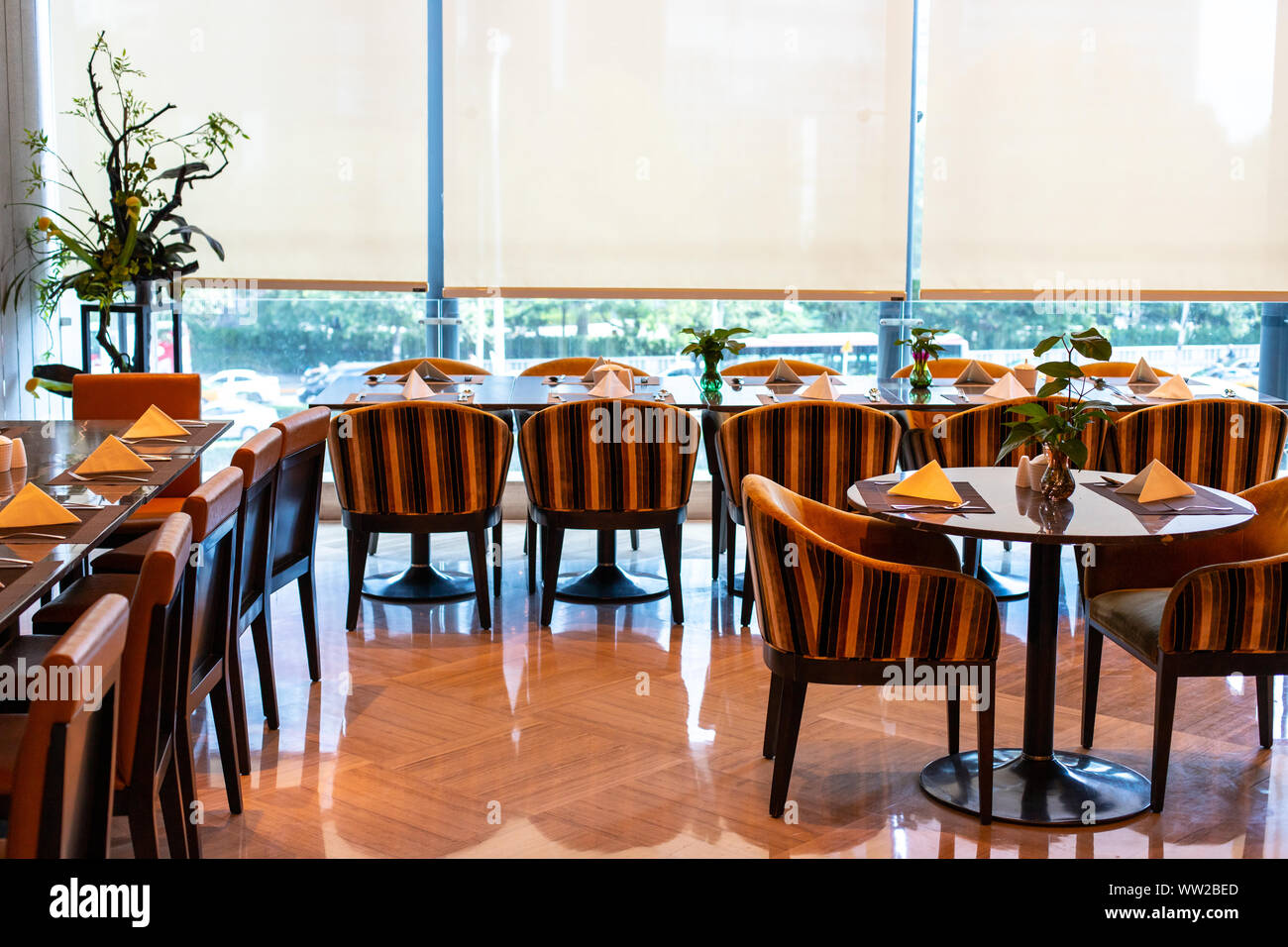 Serviert Tische im Restaurant des Hotels. Der Bankettraum ist bereit, Gäste zu empfangen. Rollos weggelassen und einer chinesischen Pflanze in der Ecke. Stockfoto