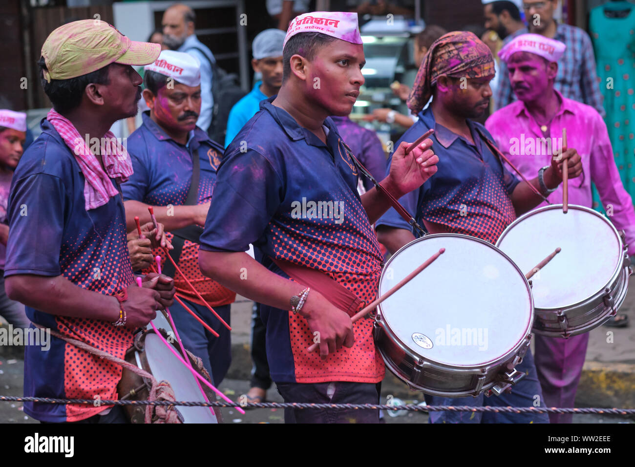 Eine Gruppe von Trommlern in farbigen Gulal (gulaal) Pulver bedeckt, in einer Prozession während Ganesh Chaturthi (Ganesh Festival) in Mumbai, Indien Stockfoto