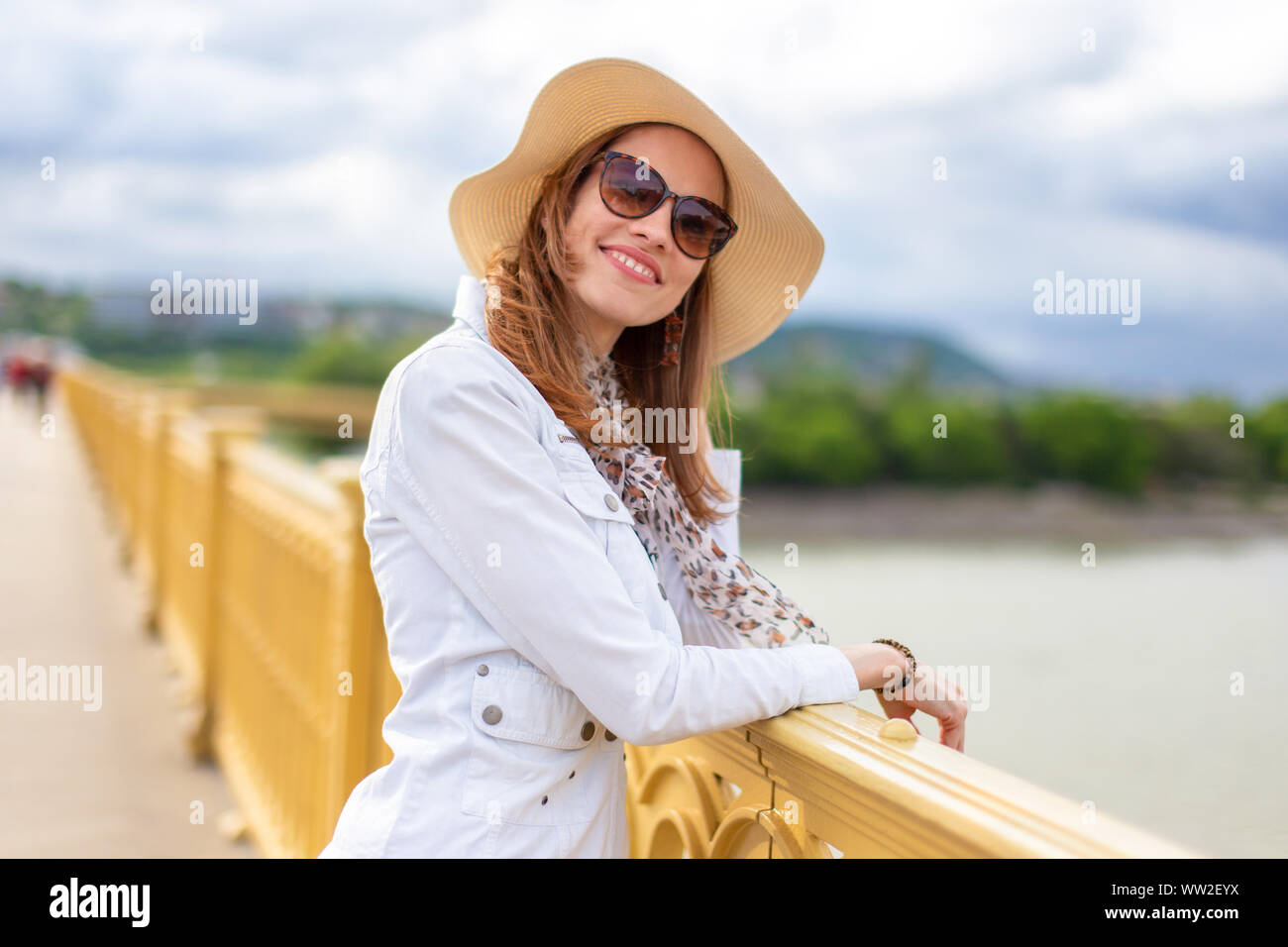 Natürliche Schönheit Frau in Hut lächelnd und entspannt auf Brücke über die Donau, Margaret Brücke, Budapest, Ungarn Stockfoto