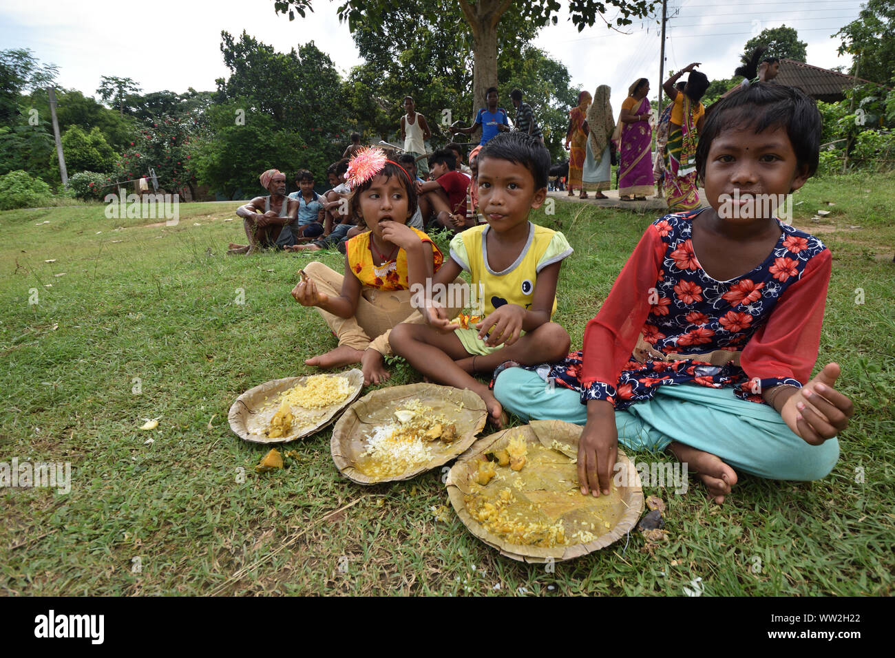 Drei Mädchen sind unter Berücksichtigung der open air Mittagessen auf dem Boden. Jhargram, West Midnapore, Indien. Stockfoto