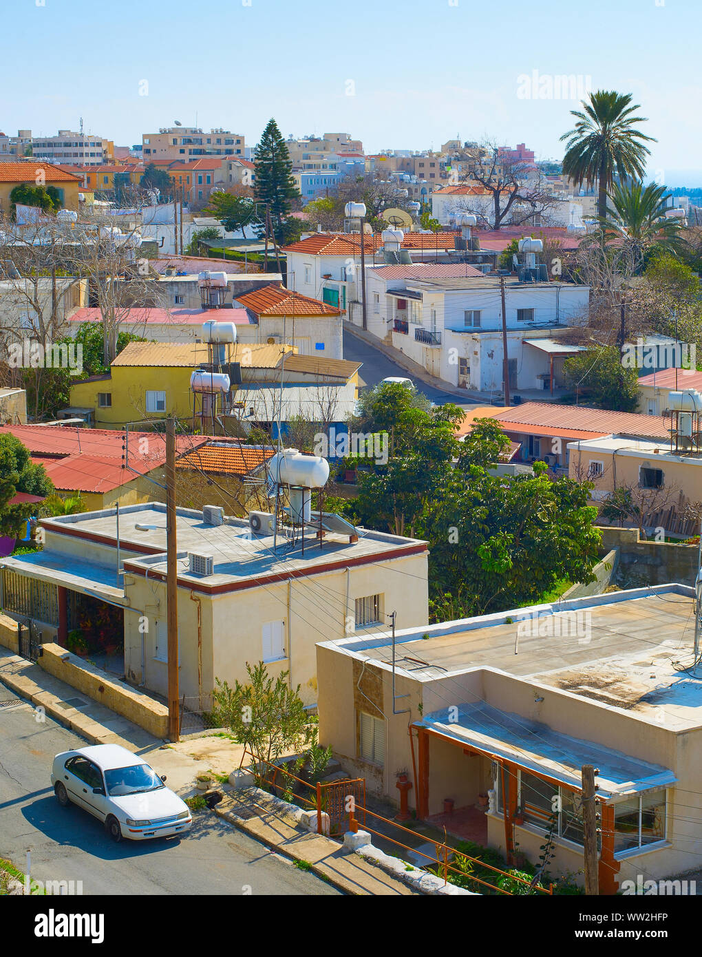 Antenne Skyline von Paphos Stadt im Sonnenlicht, Auto auf der Straße zwischen den Häusern der typischen Architektur, Palmen und grünen Bäumen, Zypern Stockfoto