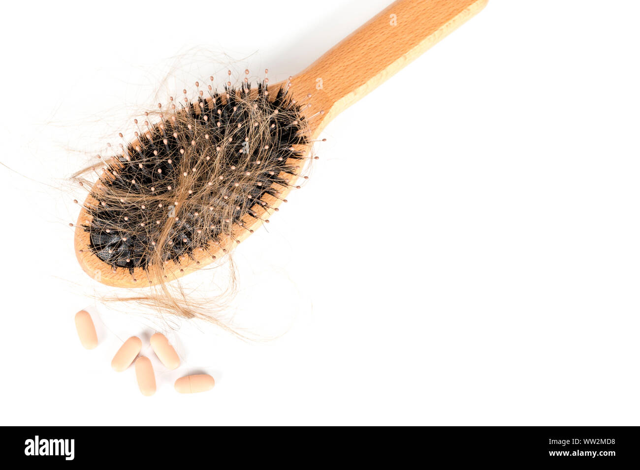 Holz Haarbürste auf weißem Hintergrund. Close-up mit langen braunen Haaren und Tabletten Haarausfall Behandlung Medizin veranschaulichen. Haarausfall Problem. Gesundheit ca Stockfoto
