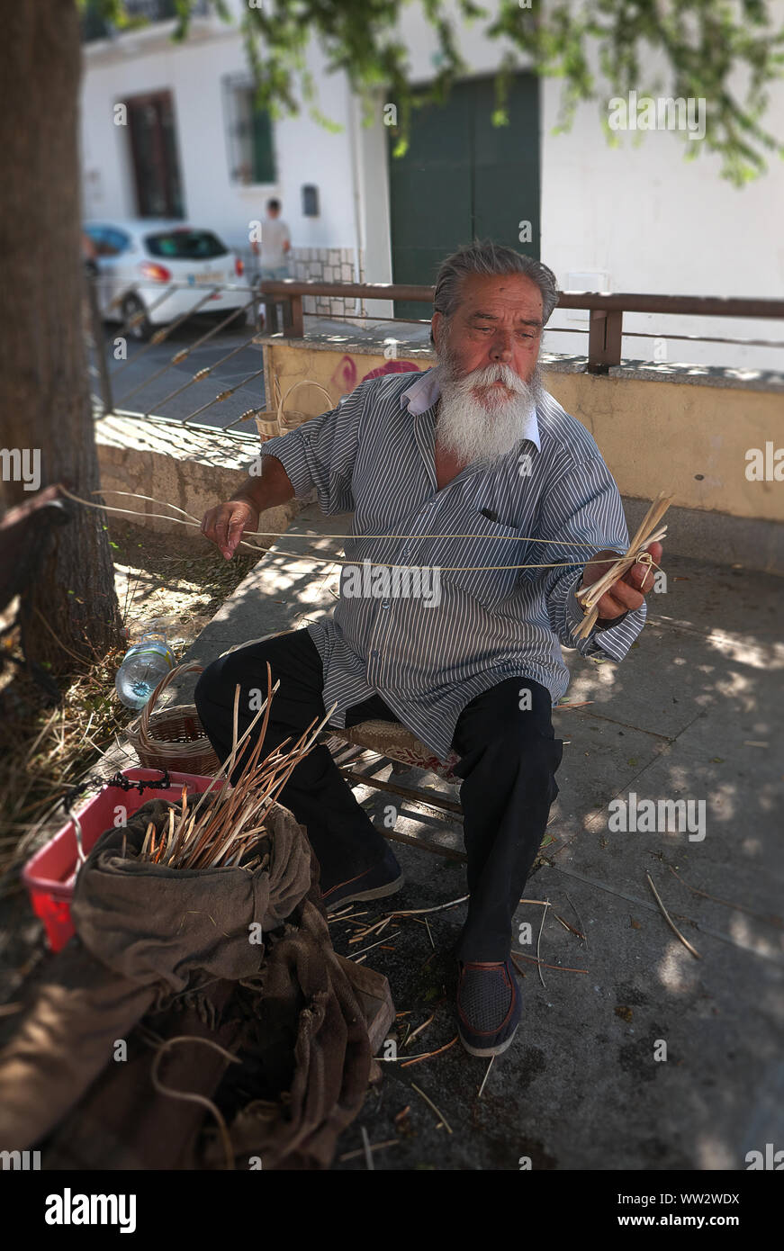 Angesehener Zigeuner Handwerker mit einem beeindruckenden Bart tun traditionellen Korb Weberei auf dem Dorfplatz kleines Dorf in Spanien Stockfoto