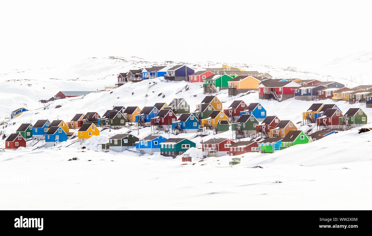 Mehrere bunte Inuit Häuser und Bungalows auf dem Hügel mit Schnee bedeckt, Aasiaat Stadt, Grönland Stockfoto