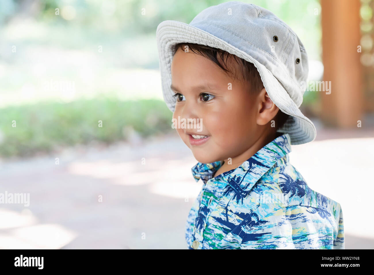 Ein kleines Kind; 3 Jahr alt, mit Hut und Hawaiian Shirt drucken, in die Ferne schauen, mit einem netten Lächeln auf dem Gesicht. Stockfoto