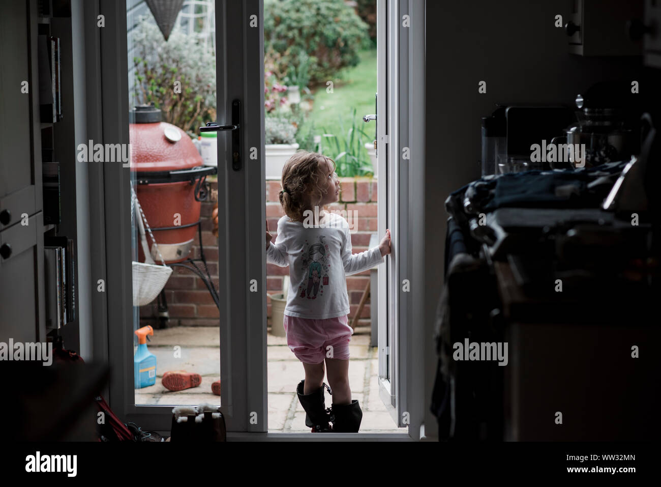 Junge Mädchen stand in der Tür außerhalb des Regen suchen Stockfoto