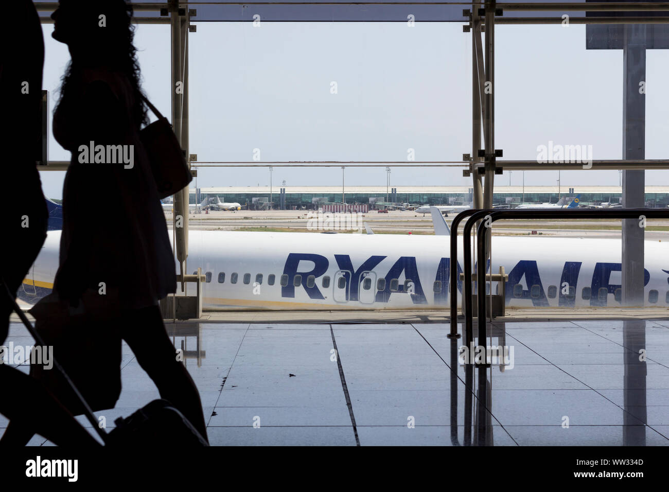 Passagiere mit Gepäck im Flughafen Terminal mit Ryanair Flugzeug im Hintergrund Stockfoto