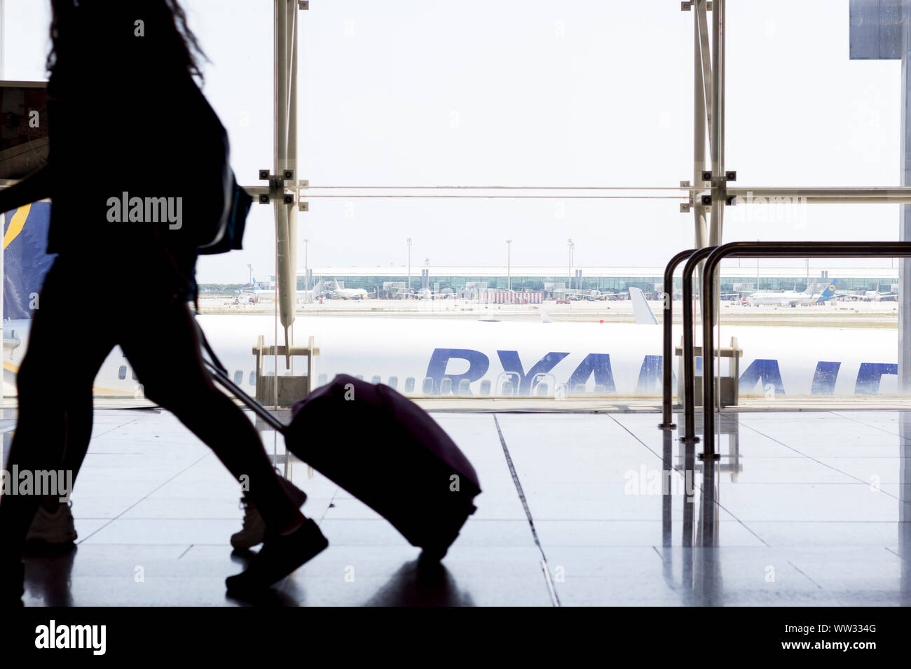 Passagiere mit Gepäck im Flughafen Terminal mit Ryanair Flugzeug im Hintergrund Stockfoto