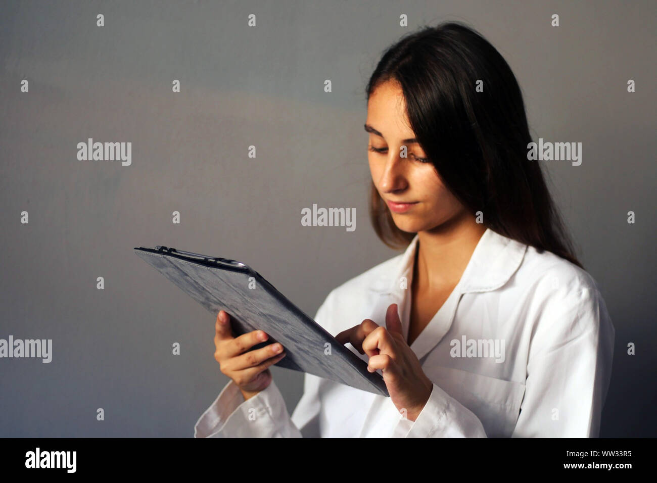 Medizin Konzept: junge Ärztin auf grauem Hintergrund mit einem digitalen Tablet. Healthcare Technologie. Stockfoto