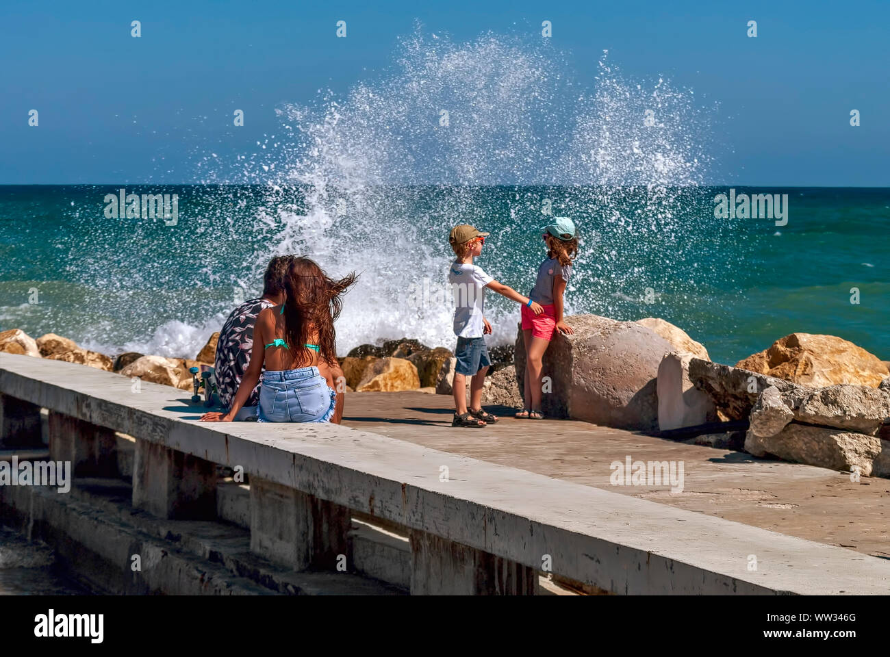 Kinder spielen auf der Pier unter dem Spritzwasser der Wellen im Meer, Schwarzes Meer Bulgarien; Stockfoto