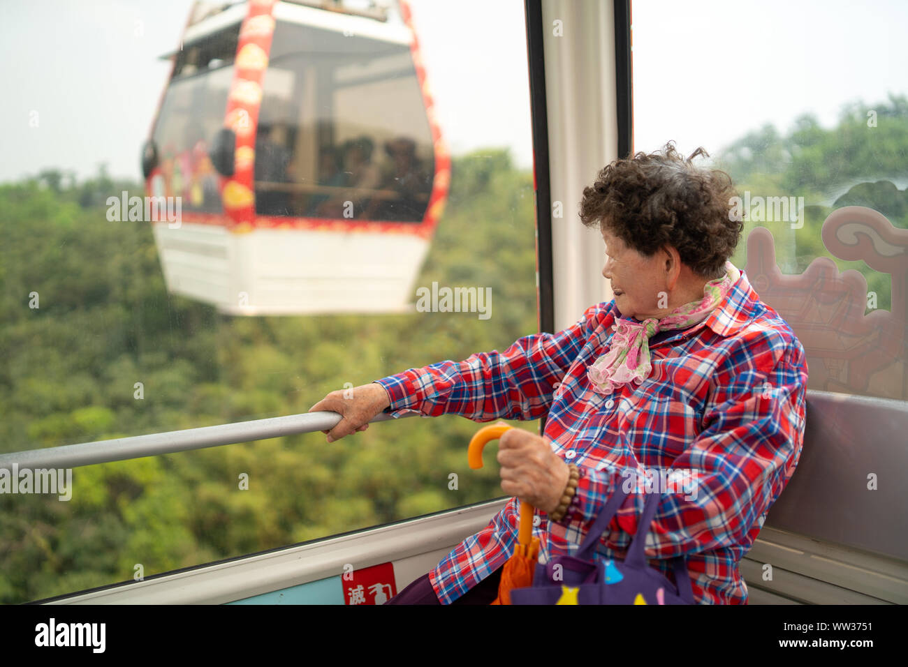 Taipei, Taiwan - 09. April 2019: Taiwanische grandma Blick aus Fenster und genießen Sie die Fahrt mit der Gondel Maokong, zweite Gondel außerhalb Fenster Stockfoto