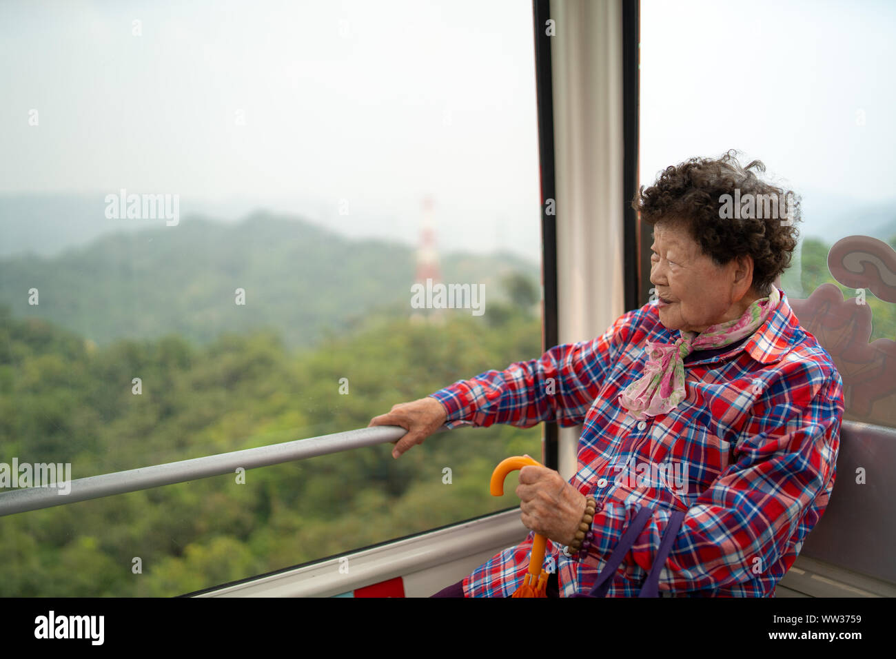 Taipei, Taiwan - 09. April 2019: Taiwanische grandma Blick aus Fenster und genießen Sie die Fahrt mit der Gondel Maokong Stockfoto