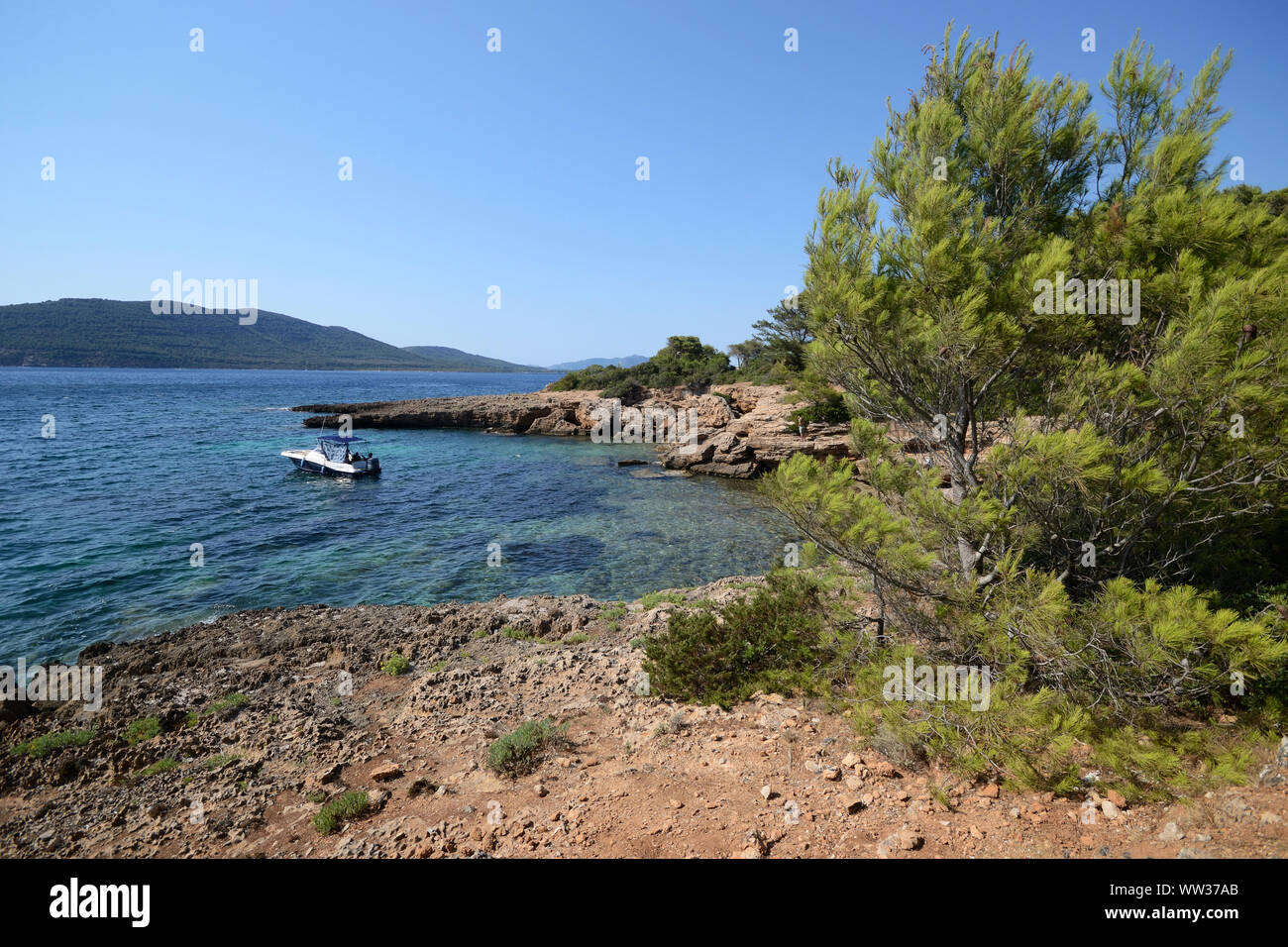 Ein Motorboot in der Nähe von Cala Bramassa, einer kleinen Bucht an der sardischen Meer verankert, in der Porto Conte Natural Park, an einem sonnigen Sommertag Stockfoto