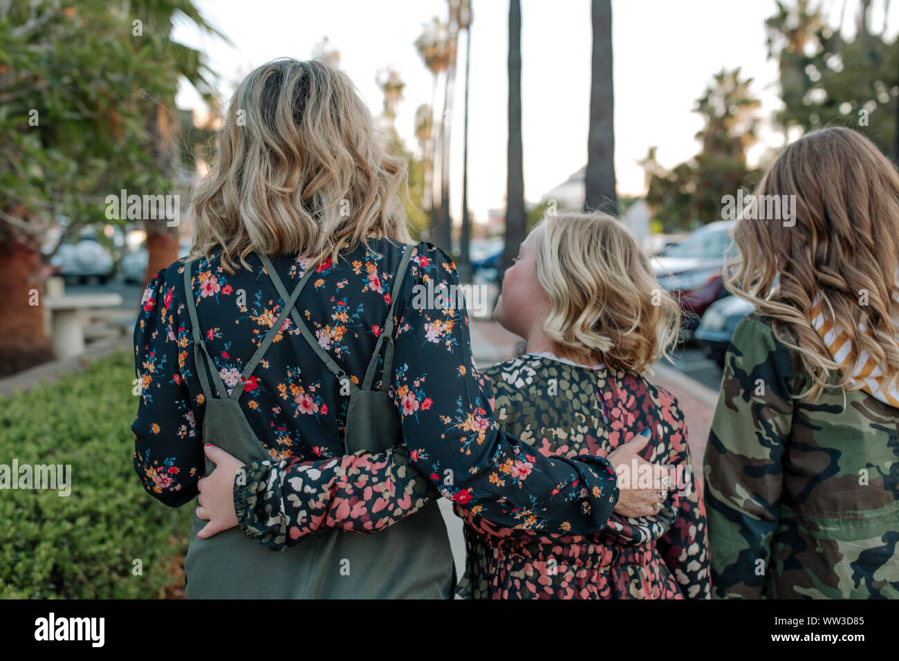 Mutter und Töchter zu Fuß die Straße runter mit Palmen Stockfoto