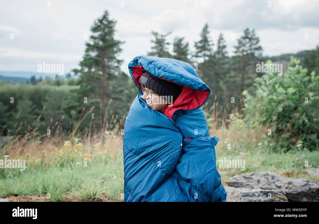 Porträt einer Frau, die in einem Schlafsack beim Camping im Freien gewickelt Stockfoto