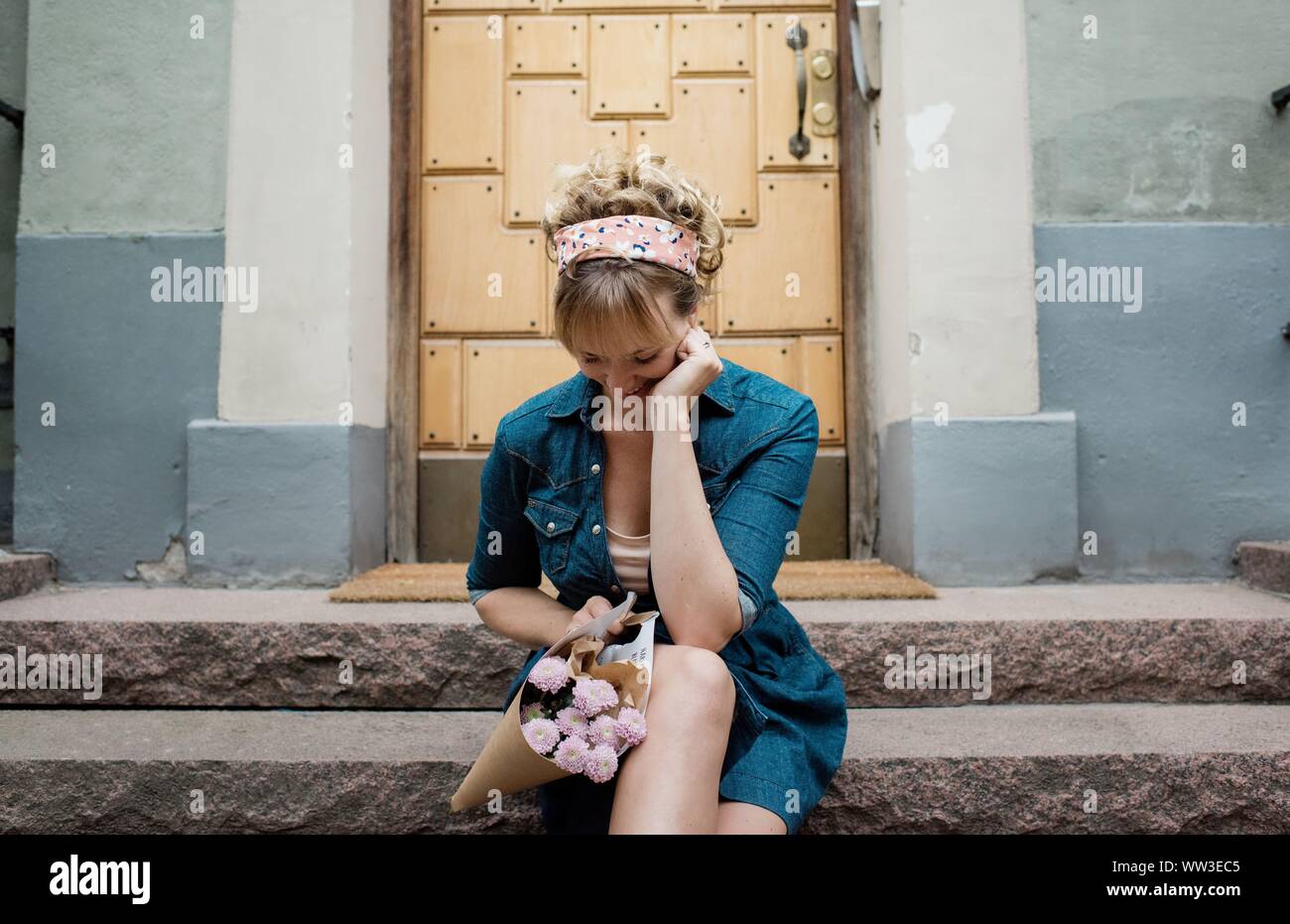 Blonde Frauen sitzen auf einem Schritt warten, mit Blumen in der Stadt Stockfoto