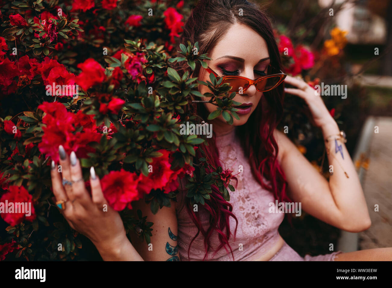 Junge Frau mit Vintage Style sitzen unter Blume Bush Stockfoto