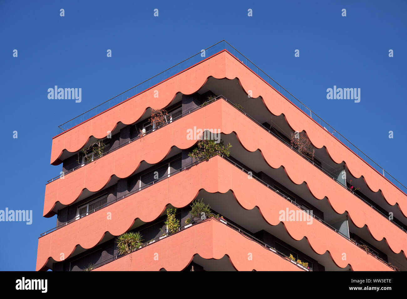 Nahaufnahme von roten Gebäude mit Wellenlinien Balkon im Winkel. Ansicht der oberen drei Etagen Stockfoto