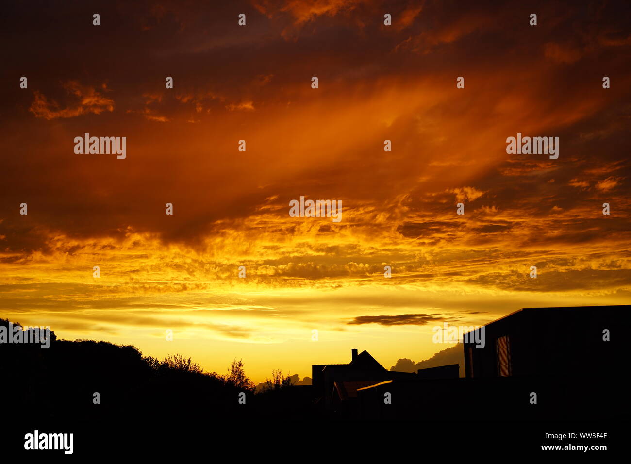 Brennender Himmel über der Stadt, Wolken wie Feuer bei Sonnenuntergang Stockfoto