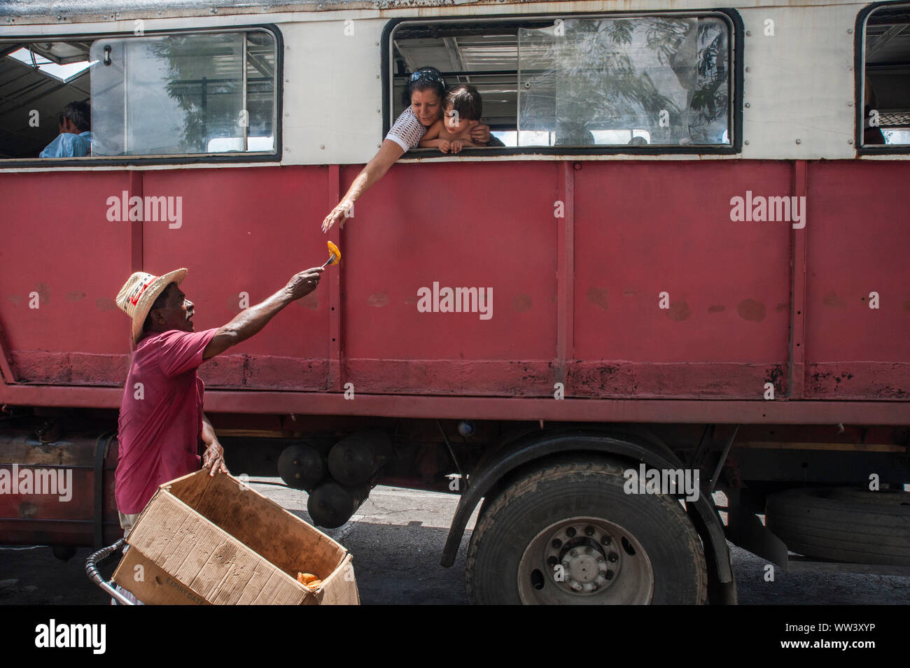In Havanna, Kuba, verkauft ein Mann Lebensmittel von einem Fahrrad an Fahrgäste in einem Bus Stockfoto
