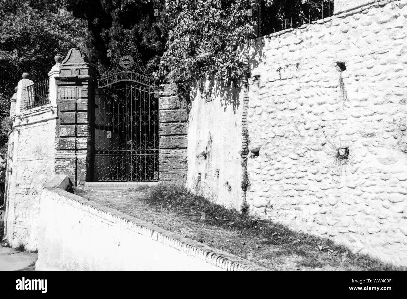 Ein weißer Zaun aus Stein, der ein Regierungsgebäude umgab, mit einem schmiedeeisernen Tor zum Eingang; Granada, Spanien. Stockfoto