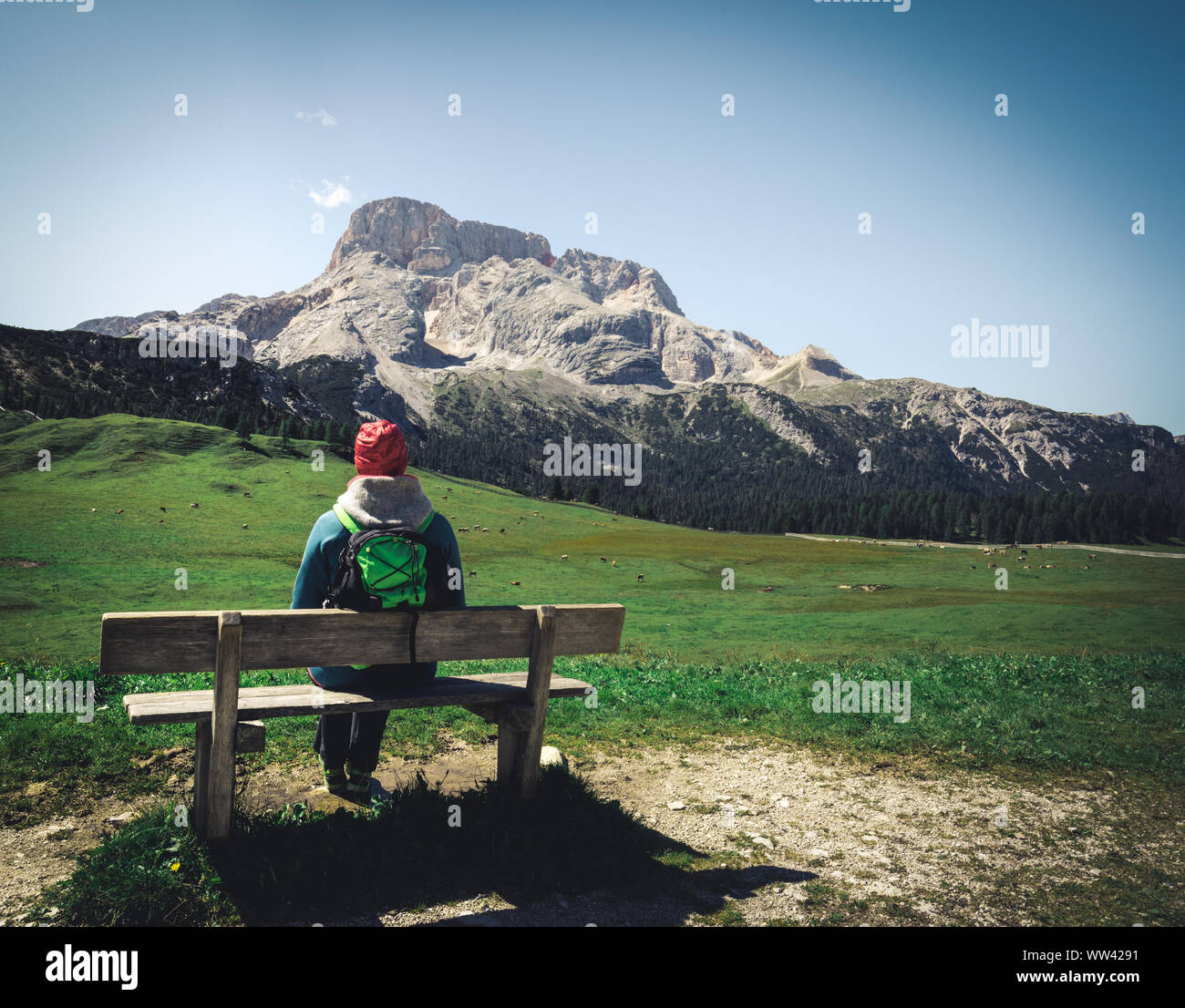 Frau sitzt auf einer Holzbank Betrachtung ein Tal in den Alpen. Ein atemberaubender Frühling von der Dolomiten. Südtirol. Italien. Stockfoto