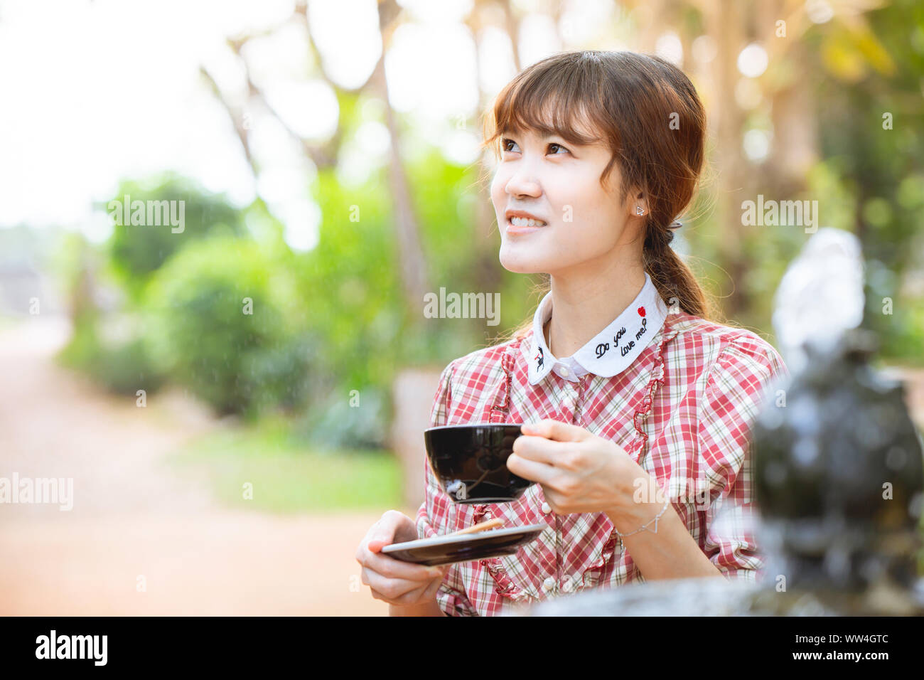 Asiatische Frau trinkt heißen Tee im Sommer morgens im Freien gutes Gefühl und Tag entspannen Stockfoto