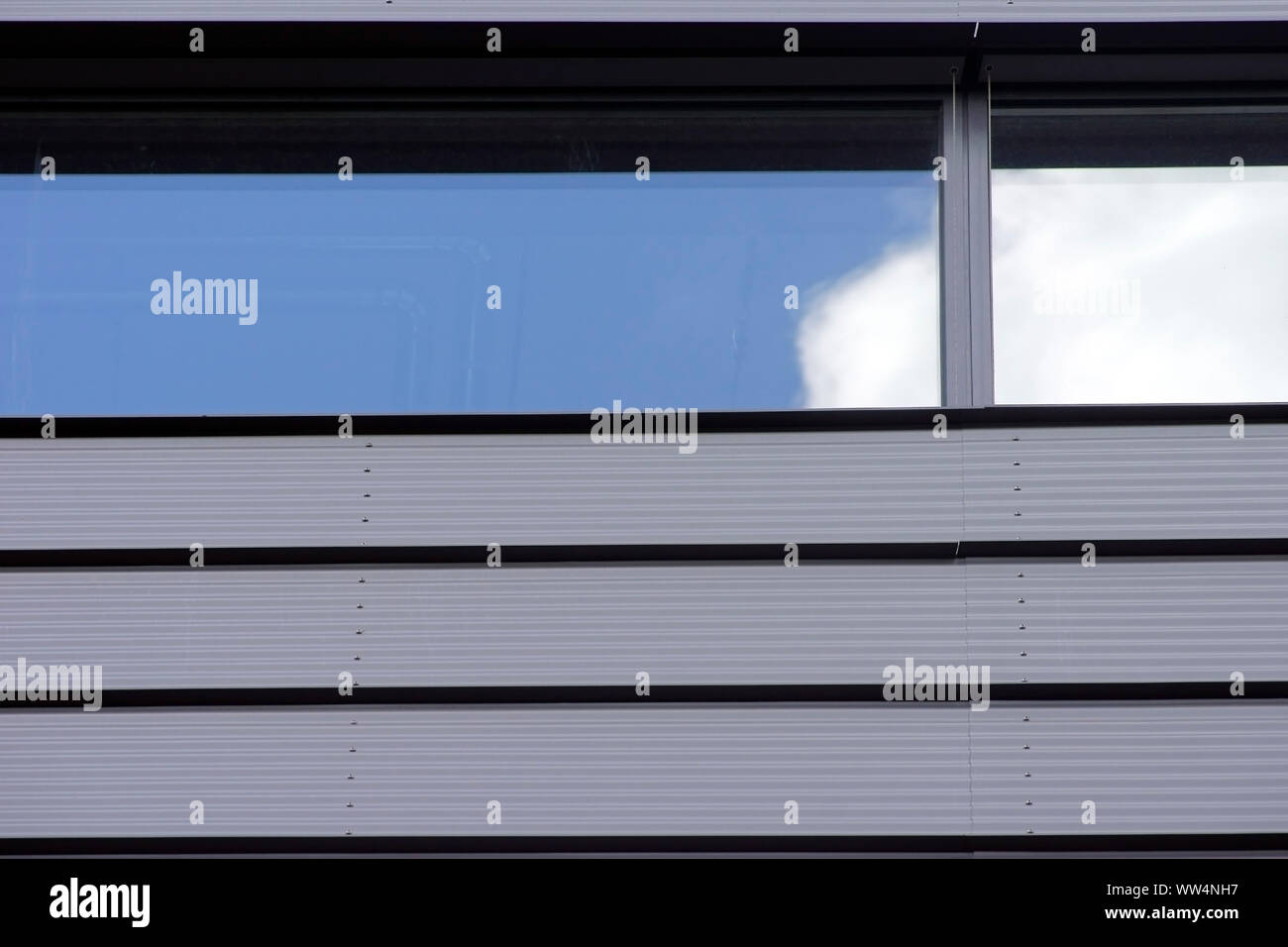 Fotografie von einem modernen Haus Fassade aus Wellblech mit einem Fenster spiegelt den Himmel und Wolken, Stockfoto