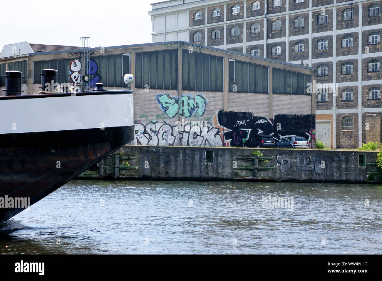 Fotografie von einem Schiff hinten an ein Lager mit Graffiti bemalt, Stockfoto