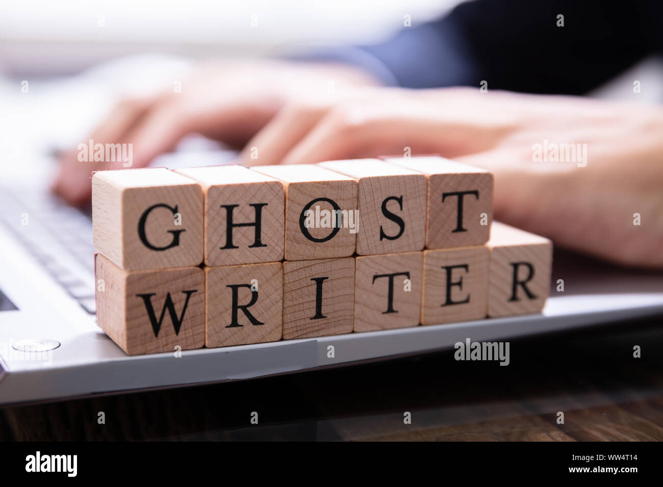 Ghostwriter Holzklotz auf dem Computer Tastatur, während jemand eingeben Stockfoto
