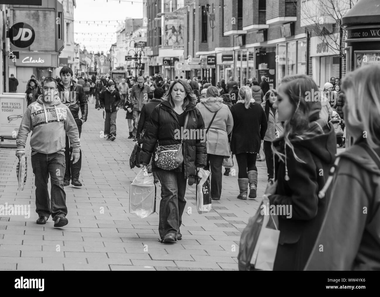 Schwarz-weiß-Ansicht von Menschen zu Fuß durch eine geschäftige Fußgängerzone mit Einkaufszentrum in Worthing, West Sussex, England, UK. Stockfoto