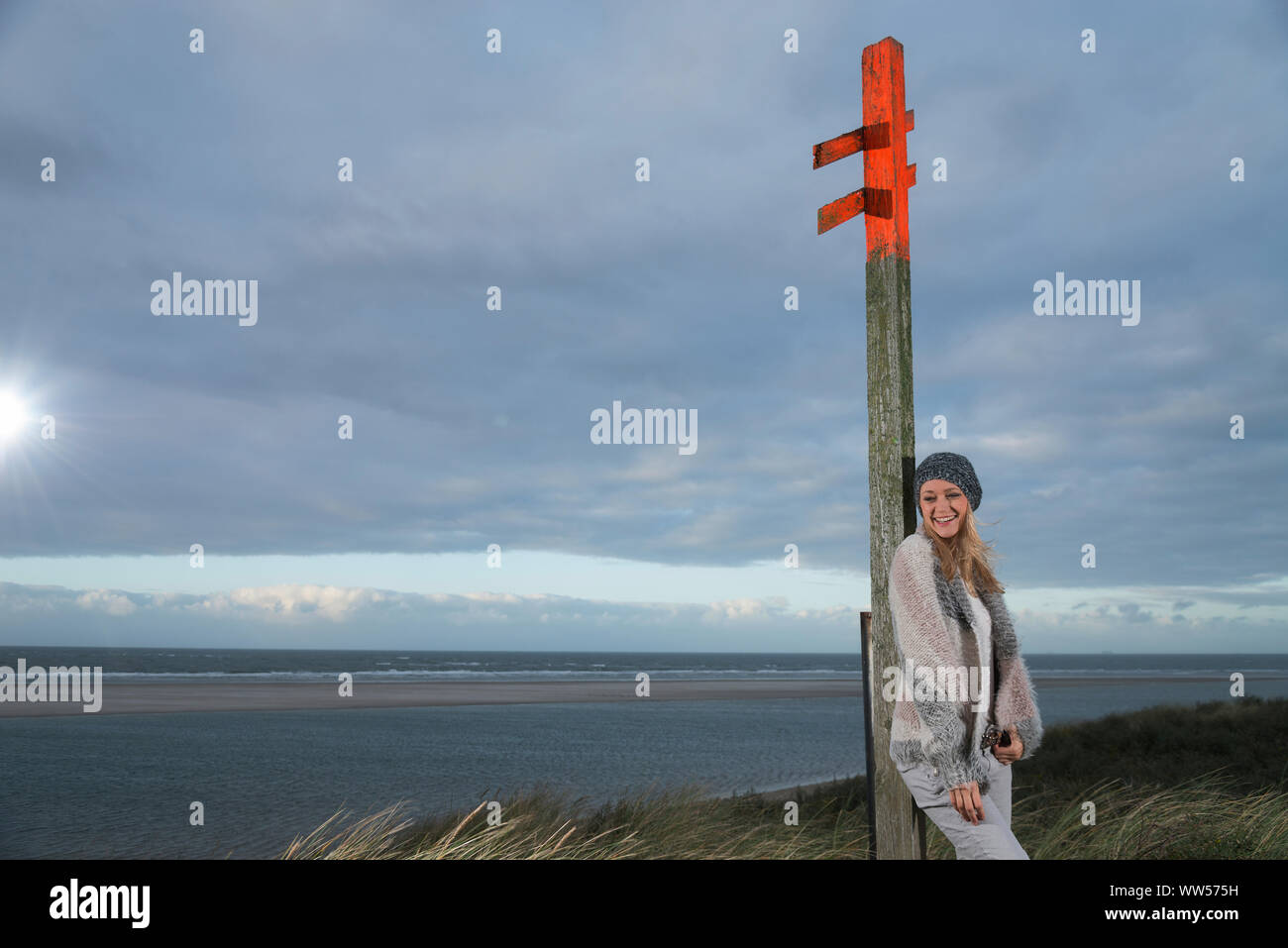 Frau lehnte sich gegen eine Säule in der Nähe des Meeres Stockfoto