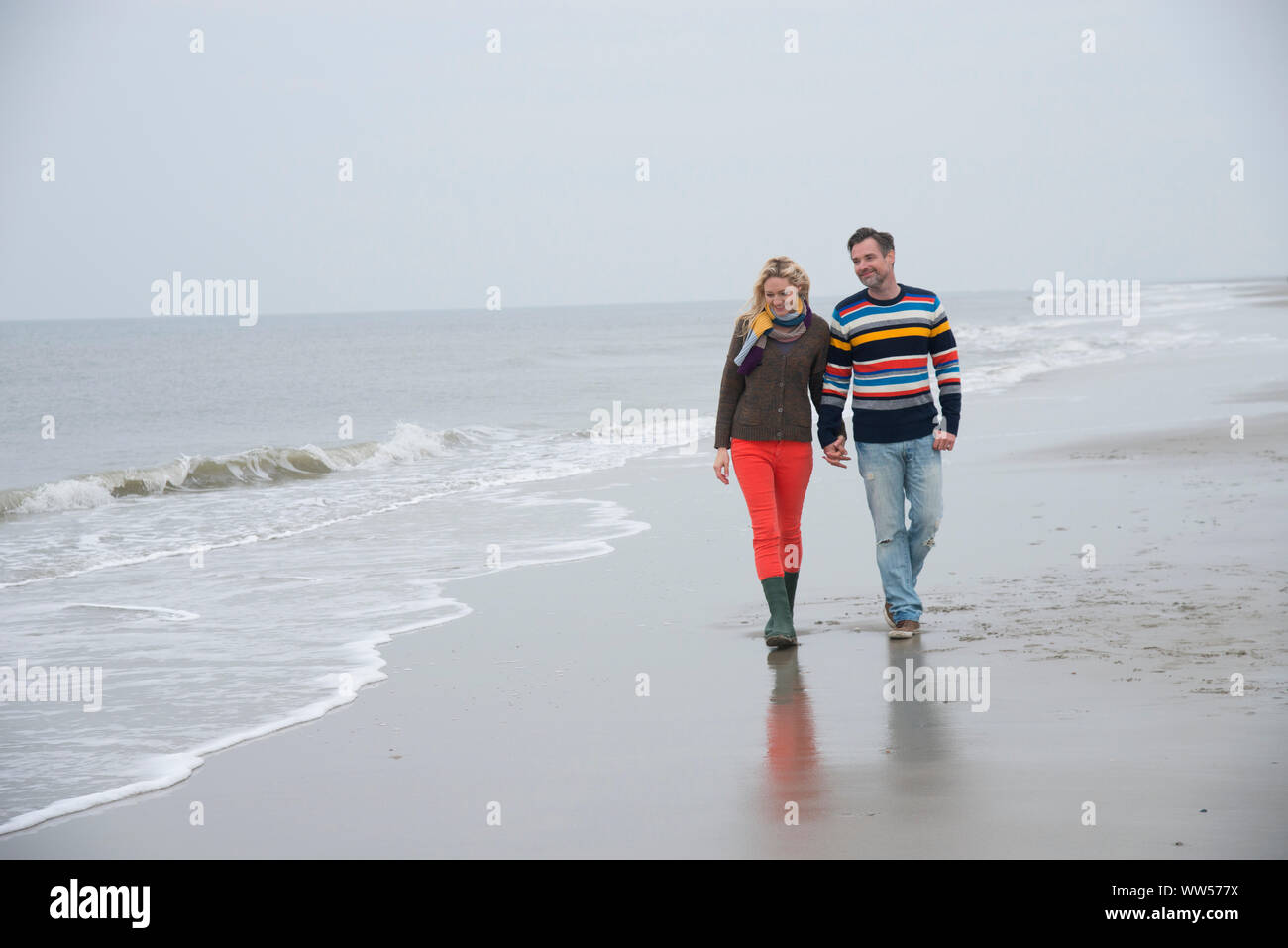 Paar mit herbstlichen Kleidung zu Fuß am Strand entlang Stockfoto