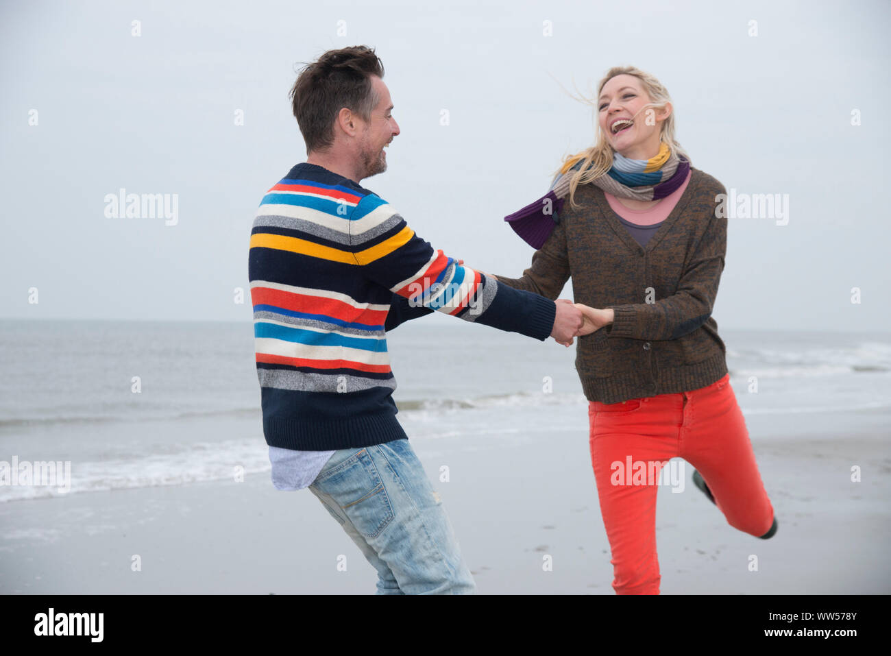 Paar halten sich an den Händen und Tanzen am Strand Stockfoto