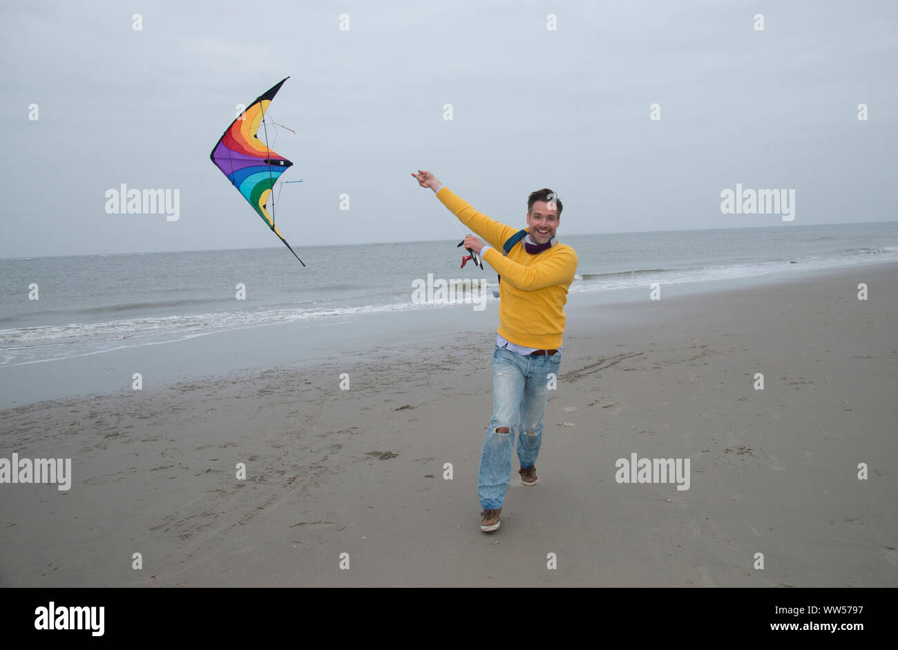 Mann laufen am Strand fliegen Lenkdrachen Stockfoto