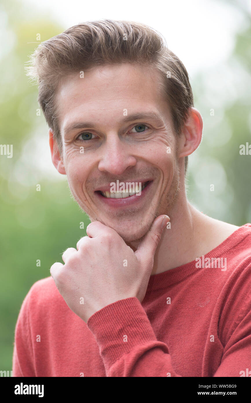 Mann im roten Pullover, Hand am Kinn, Porträt, Stockfoto