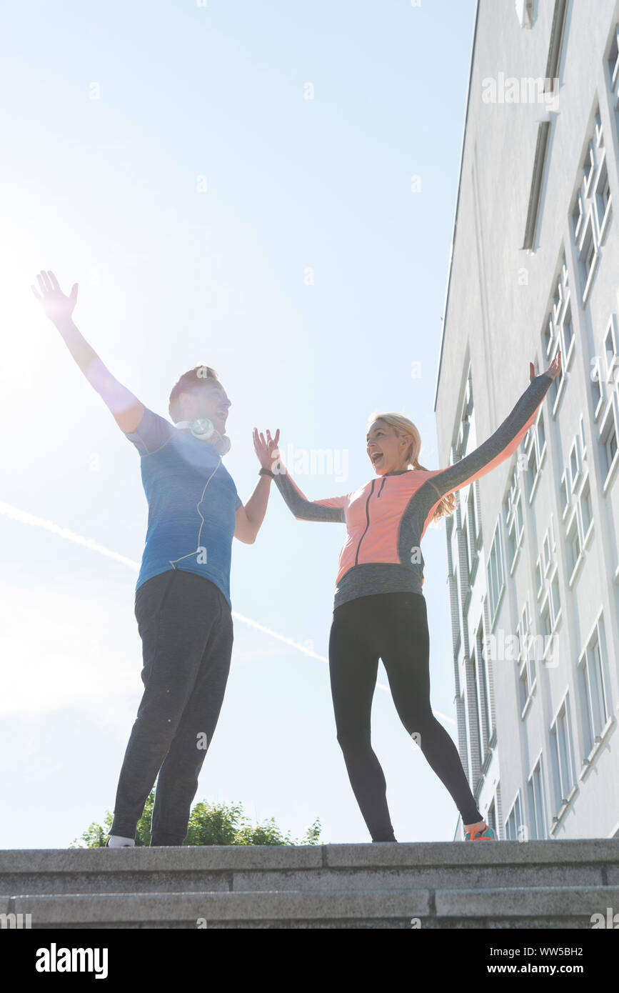 Paar in Sportswear ständigen Jubel auf der Treppe außerhalb Stockfoto