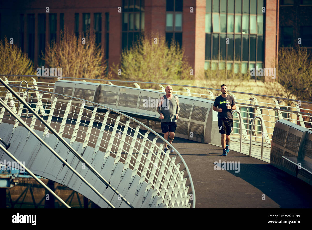 NEWCASTLE UPON TYNE, England, Großbritannien - 08.Mai 2018: Zwei Läufer über die Millennium Bridge an der Morgensonne. Stockfoto