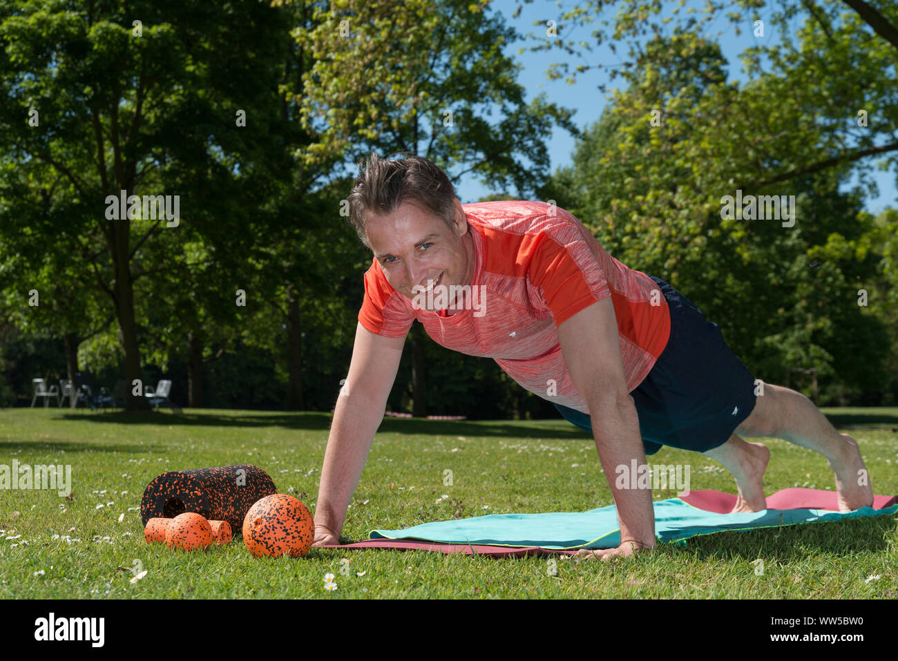 Mann in Sportswear im Park, Gymnastik, Push-ups auf Matte Stockfoto