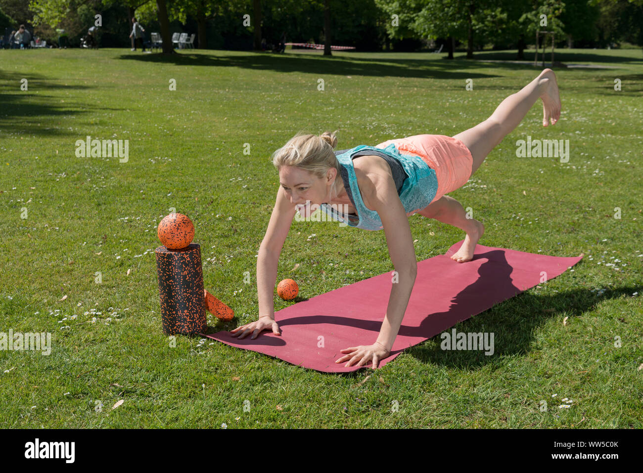 Frau in Trainingskleidung mit Gymnastik Bälle auf pink Matte im Park Stockfoto